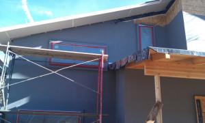 A liquid-applied water barrier covers the walls, serving as a drainage plane, air and vapor barrier, and secondary window flashing beneath the rigid foam that will be installed next.