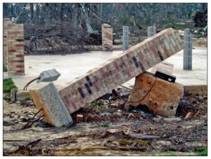 The brick house foundation piers on discrete footings (in the foreground) failed by rotating and overturning while the piers set in the concrete mat survived Hurricane Katrina. 