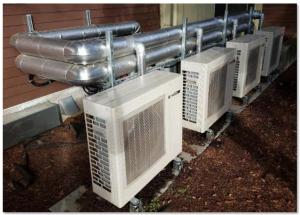 This fully specified central heat pump water heating system has four individual outdoor heat pump units plumbed in parallel to indoor storage tanks 