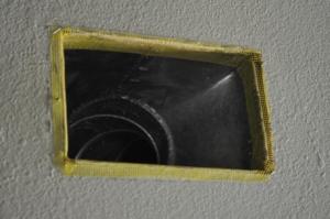 Fiberglass mesh tape is installed around a duct boot in preparation for air-sealing the seams with mastic.