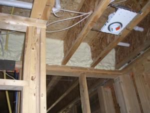 Right – Closed-cell spray foam insulates and air-seals the rim joist above a shared wall between the garage and living space.