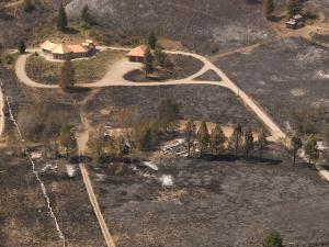 Defensible space and ignition resistant building materials saved this home from a wildland fire that destroyed the neighboring home in the foreground 