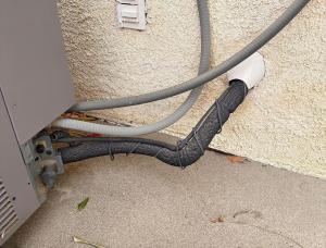 The pipe insulation on this exterior refrigerant line is intact but significantly degraded from ultraviolet (UV) exposure.