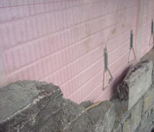 Drainage behind stone cladding is provided by “grooved” rigid insulation coupled with a filter fabric.