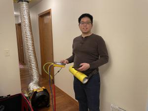 The energy rater has set up the duct leakage test by attaching the test duct to the home's return register and attaching the manometer to the fan.