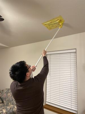 After completing the air leakage tests, the energy rater uses a broom handle to remove the register-sealing tape.