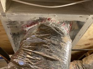 The large hole that was cut in the subfloor penetration for this HVAC duct has been air-sealed using sheet metal, mastic, and metal tape.