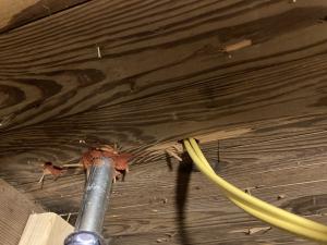 The electrical conduit (metal) on the left has been sealed to the subfloor using fire-rated caulk, while the penetration for the yellow electrical wire on the right has not been air-sealed yet.
