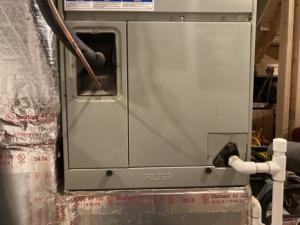 The filter access panel on this vertical upflow air handler is located between the return ductwork below and the coils above.