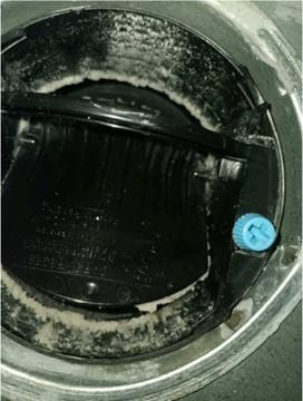 This constant airflow regulator (CAR) has been fouled by aerosolized sealant because it was not covered while the ducts were being sealed with the aerosolized acrylic sealant. 