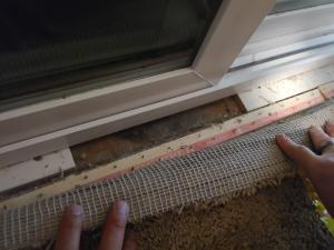 Pulling the carpet back reveals a large gap between the shims under the frame of this sliding glass door 