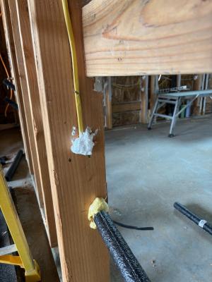 Right - The plumbing and wiring holes in this garage-to-house wall have been air sealed with spray foam