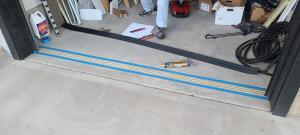 Garage door threshold weatherstripping is ready to be installed on the garage floor beneath the garage door.