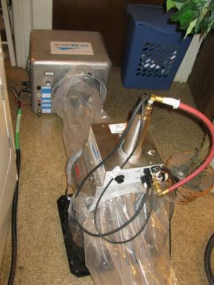 The duct sealing spray injection system includes a blower/heater (background) and the sealant injection unit (foreground)