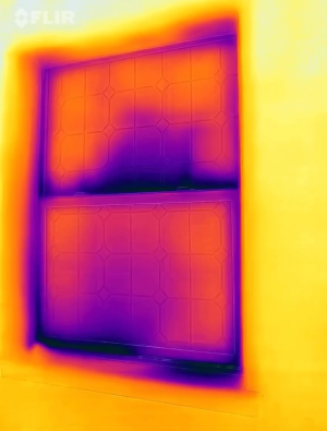 The dark purple patches at the sill and streaks at the meeting rail of the window in this IR camera image indicate heat loss and significant air leakage.