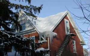 The icicles and the bare spot along the left roof ridge indicate that heat from the second-story room may be heating the underside of the roof deck, melting the snow and likely leading to ice dam formation.