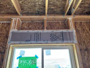 This window header has been insulated with rigid foam and air sealed with house wrap tape and all wood-to-wood joints are caulked.