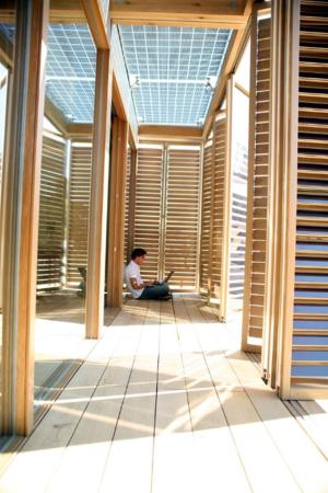 These folding louvered porch doors provide effective shade from low-angle east and west sunlight and can open for views; the photovoltaic panels overhead allow in filtered natural light