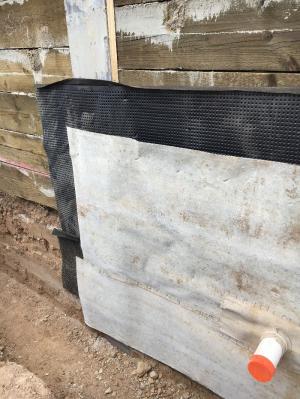 Right - The service penetration in the waterproofing membrane is well-sealed, and there is a drainage mat acting as a protective layer on the interior of the soldier piles and wood lagging. 