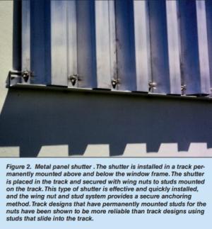 A metal storm panel is installed in a track permanently mounted above and below the window frame and secured with wing nuts to studs mounted on the track.