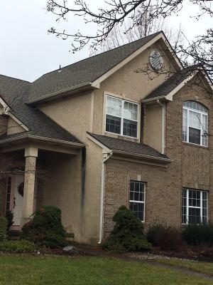 Wrong - Missing kick-out flashing to divert rainwater runoff away from the house and into the gutter where the roof meets the wall has caused discoloration of the stucco and water damage behind the stucco by the front porch and the second-story window. 