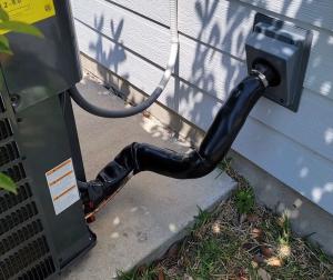 The refrigerant line for this outdoor compressor unit of the home’s air conditioner is covered  with new pipe insulation then wrapped with an additional UV-resistant jacket to protect it from the elements.