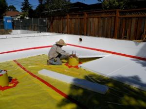 The builder laid down a 4-inch base of aggregate rock, then covered that with a plastic vapor barrier that is taped at all seams and around all penetrations before installing the rigid foam under-slab insulation.