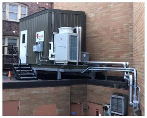 Central heat pump water heaters like this fully packaged system provide efficient, reliable domestic hot water for multifamily buildings; storage tanks are within the enclosure, and the heat pump is seen just outside.