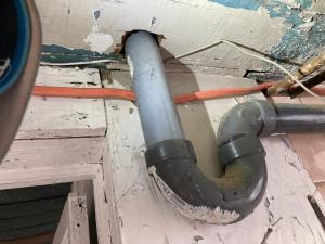 The large hole in the subfloor for this sink drain is a source of air leakage and should be sealed using canned spray foam.