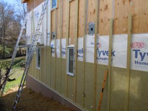 Holes in the exterior walls are flashed and flashing is integrated with housewrap before installing rigid mineral wool insulation.