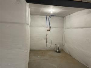 Right - The blanket fiberglass insulation is installed over a continuous layer of rigid foam insulation; the fiberglass is covered with a vapor retarder that is tape sealed at the seams.