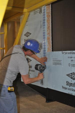 The tape is applied with even pressure to ensure the seams in the rigid foam sheathing are air sealed on this manufactured home.