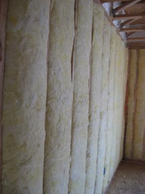 Unfaced fiberglass batt insulation is installed to completely fill the wall cavities and is sliced to fit around wiring, piping, and other obstructions in the wall cavities