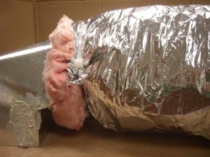 Wrong- A tie strap should not be used over the duct outer liner because it can compress the insulation. Tuck in the fibrous insulation and seal the outer liner to the connecting duct with mastic or foil tape (Steven Winter Associates 2013).