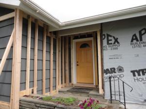 Ledger board, metal brackets, and vertical 2x4s have been installed in preparation for exterior spray foam in this retrofit exterior wall insulation technique