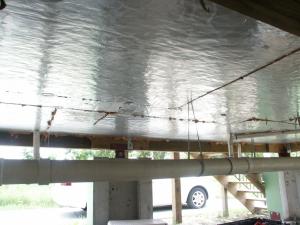 Right - Foil-faced polyisocyanurate insulating rigid foam sheathing is installed below the floor framing of this house built on piers; however, the seams should be sealed with metal taped and the plumbing elevated and protected. 
