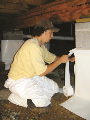 Right - A technician wraps the foundation piers with a vapor retarder in preparation for laying vapor retarder over the floor of this crawlspace. 