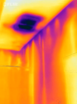 The purple streaks in this IR camera image indicate air leakage along the top plates, which is allowing cold air to be pulled from the attic into the wall cavities of this interior wall. 