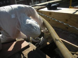 Closed-cell foam is sprayed into roof cavities along the masonry parapet wall to form a continuous air barrier between the wall and the sheathing of the flat roof