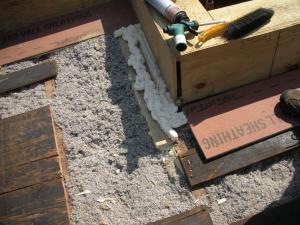 The base of the plywood parapet is air sealed with spray foam and fibrous insulation is installed in the rafter cavities in this flat roof retrofit