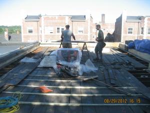 Sleepers (tapered wood furring strips) are installed over the existing board sheathing to slope the new sheathing toward the drain in this flat roof retrofit