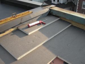 Polyisocyanurate rigid foam insulation is installed in multiple layers with staggered, taped seams over the flat roof