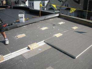 The wood blocking for future PV panel installation extends above the surface of the top layer of polyisocyanurate rigid foam insulation installed as part of a flat roof retrofit