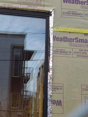 Wrong - House wrap tape is not fully adhered at seam and flashing tape is missing from window head, jamb, and corner above window.