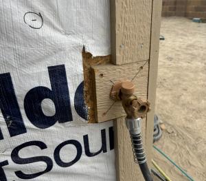 Wrong - House wrap was not cut installed under the plumbing hose bib trim and/or edges of the house wrap have not been taped so sheathing is exposed.