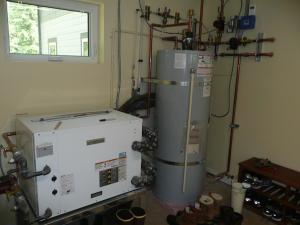 The very high efficiency (4.7 COP) ground-source heat pump provides hot water to a tank for radiant floor heat and domestic hot water.