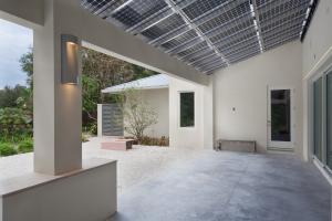 An array of 13.4 kW of solar panels form a waterproof roof for this porch that allows 15% of sunlight to filter through while the dual-surface panels produce power from the top and from any sunlight reflected up onto their lower surface.