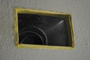 Fiberglass mesh tape is installed around a duct boot in preparation for air sealing with mastic