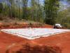 To help keep the monolithic slab-on-grade foundation dry, the site’s surfaces is graded away from the structure, the slab is poured on a bed of gravel, and using a vapor barrier will separate the foundation from the sill plates. 