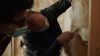 Right – an instructor shows a student how to cut batt insulation around wiring rather than compressing the batt behind the wiring. 